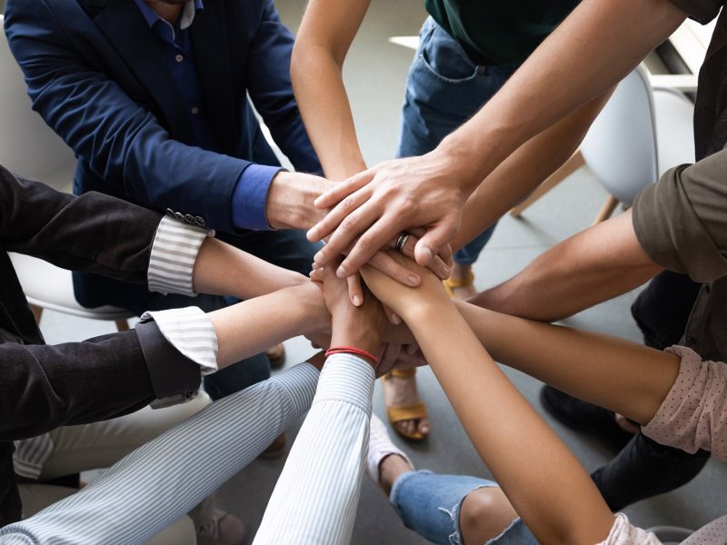 Top close up lot of hands stacked together as symbol concept of teambuilding, loyalty, amity and warm relations between office workers seminar participants, business success celebration, start of work